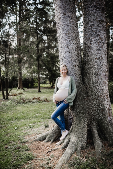 Schwangere Frau lehnt an einem Baum