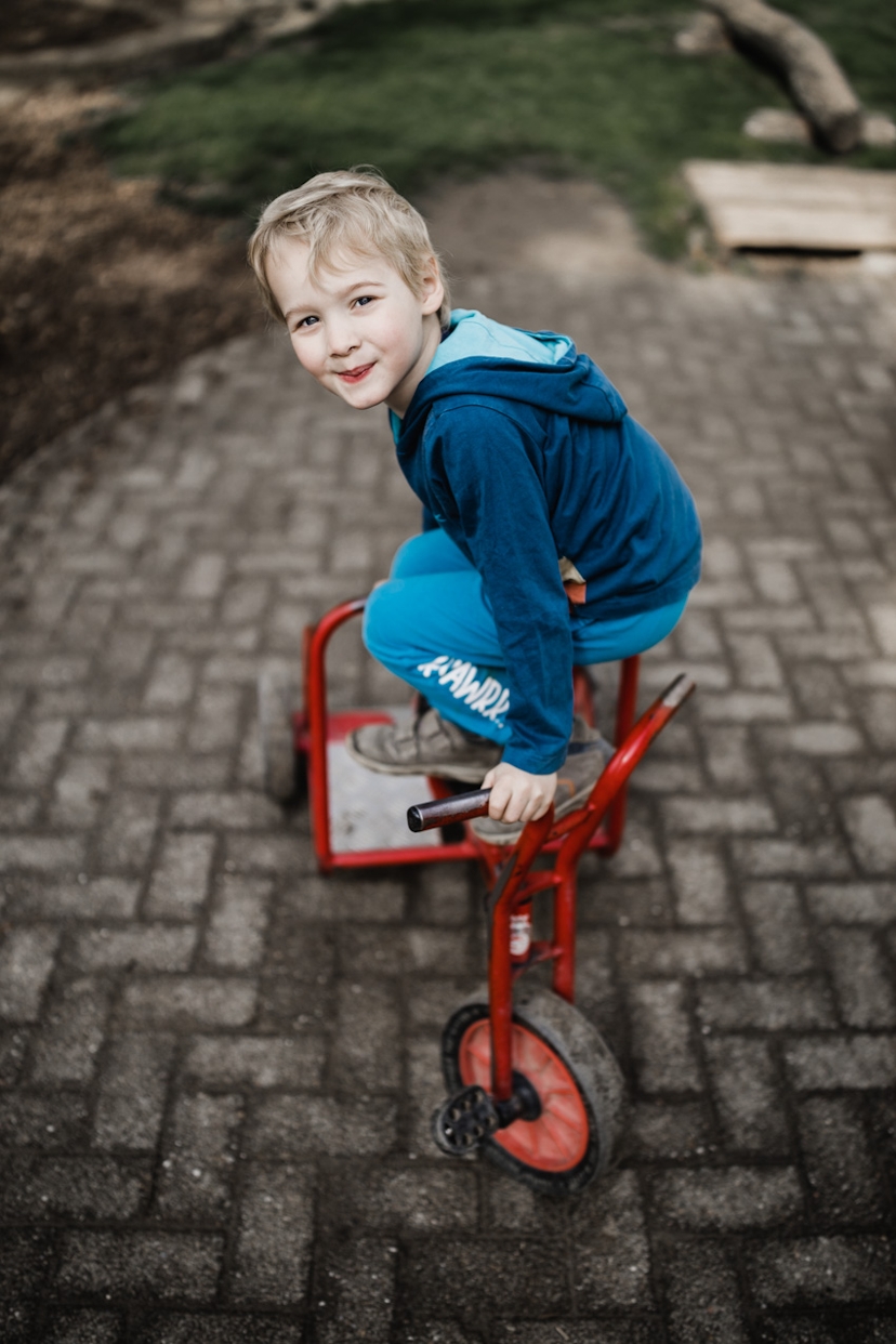 Junge steht auf einem Dreirad